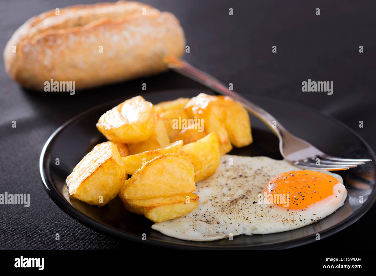 Frühstück mit gebratenen Kartoffeln und Eiern auf einer dunklen Platte Stockfoto