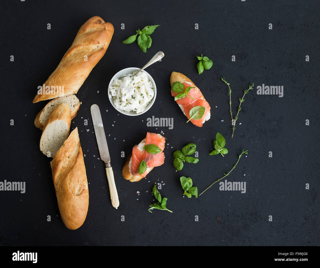 Lachs, Ricotta und Basilikum Sandwiches mit Baguette über schwarz Grunge Hintergrund. Ansicht von oben, Textfreiraum Stockfoto