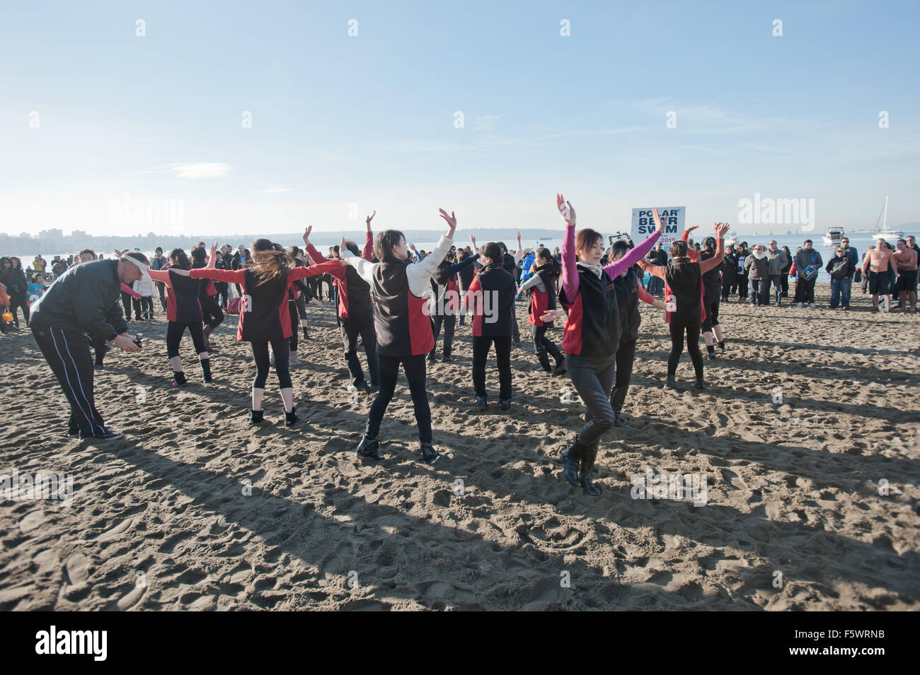 Chinesische Frauen spielen Square-Dance am Strand von English Bay vor Eisbären Schwimmen am 1. Januar 2014 Stockfoto