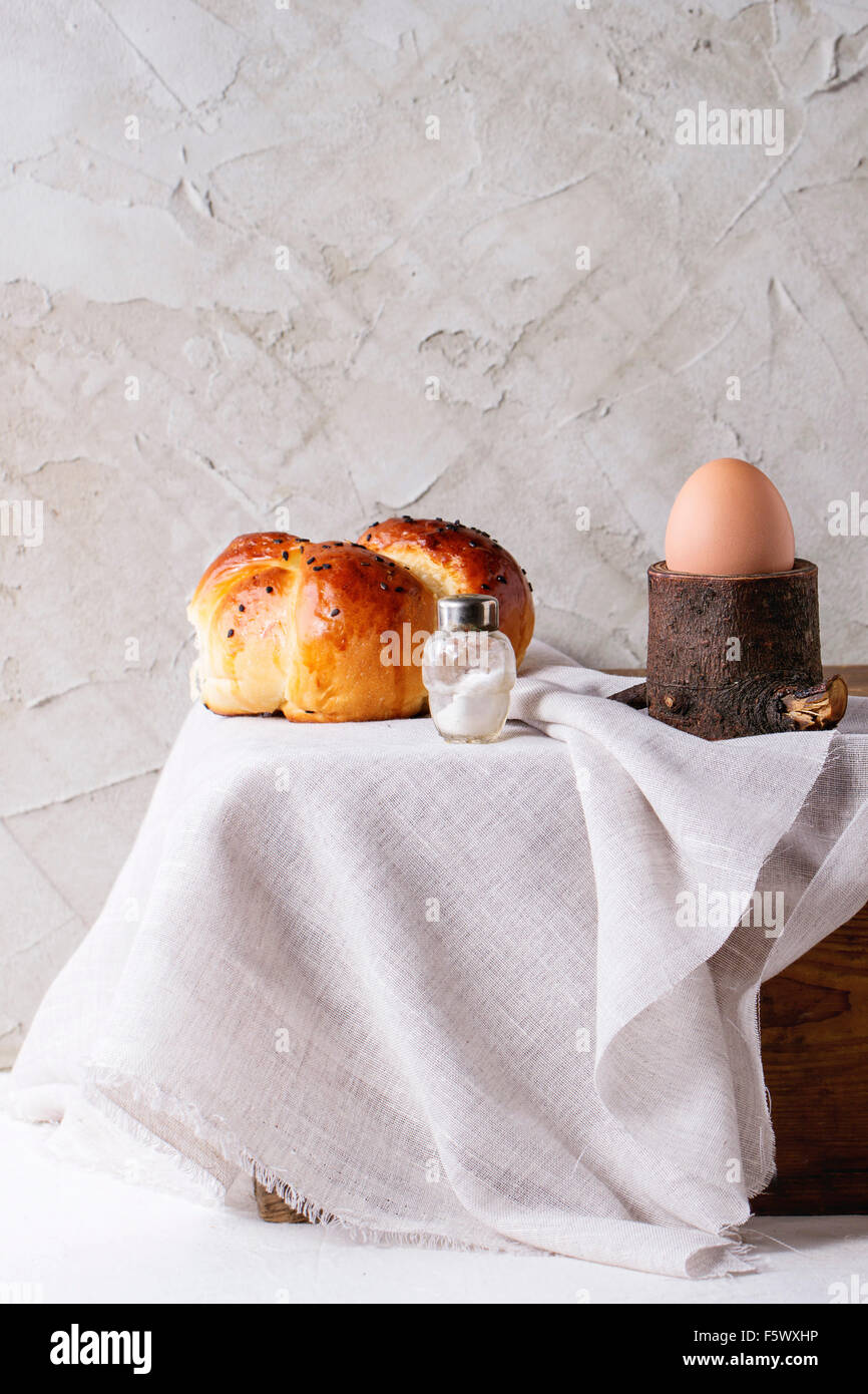 Frühstück mit ganzes gekochtes Ei in hölzernen Eierbecher und hausgemachtes Brot serviert mit Salz auf Holzkiste mit weißen Tuch über Pfingsten Stockfoto