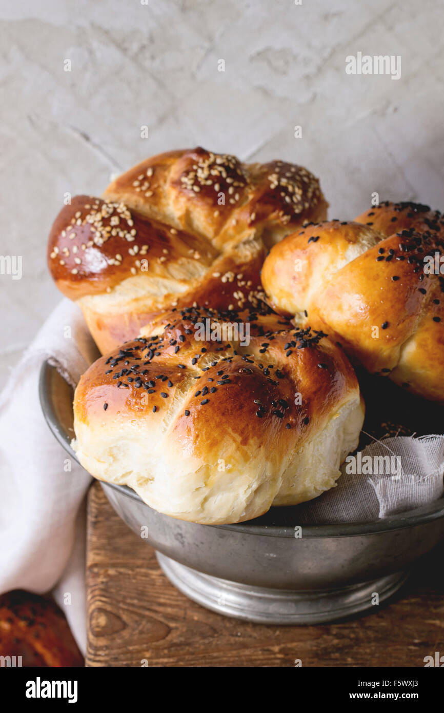 Haufen von süßen runden Sabbat Challah Brot mit weißem und schwarzem Sesam in Vintage Metallschale auf Holztisch mit verputzt Stockfoto