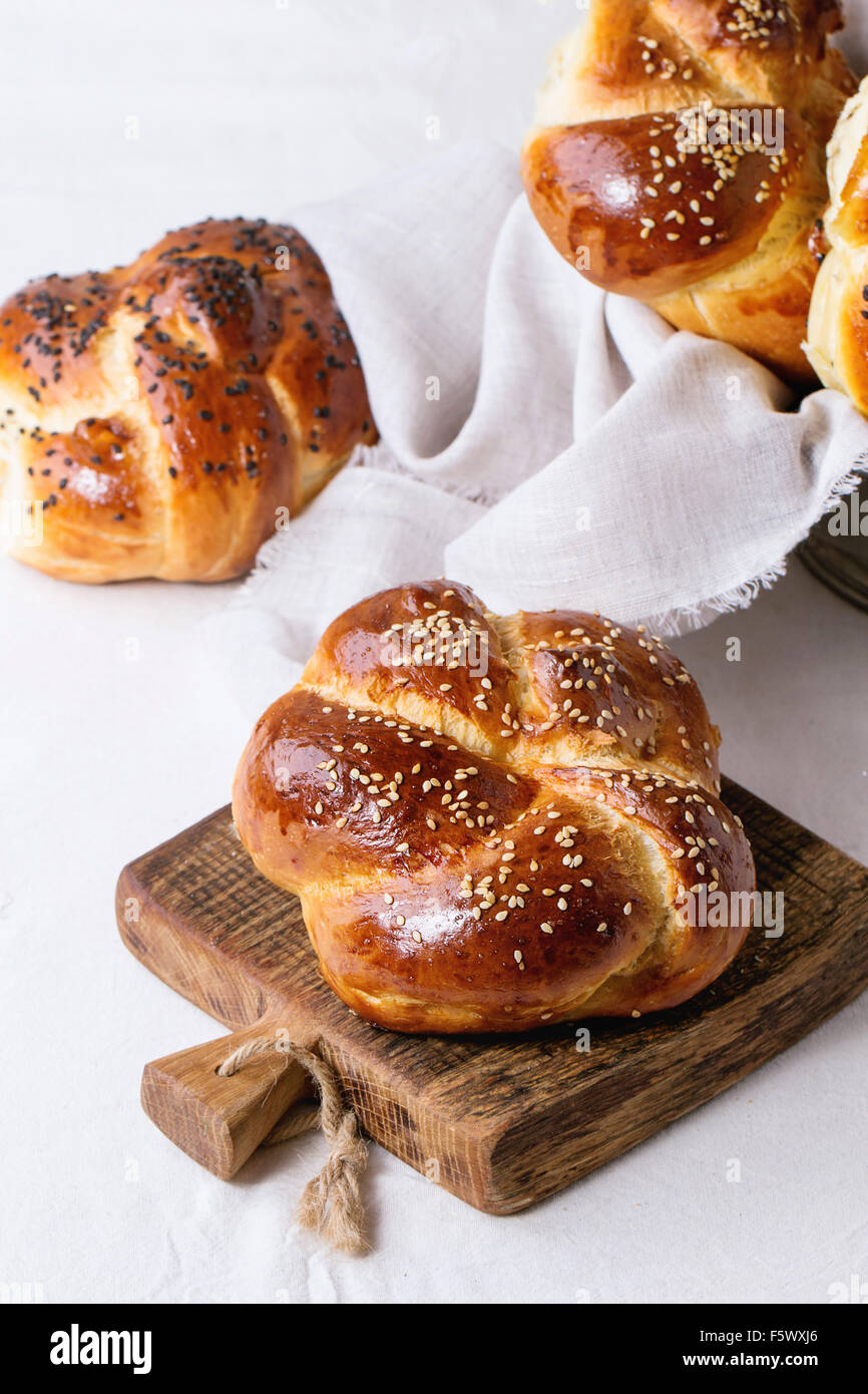 Haufen von süßen runden Sabbat Challah Brot mit weißem und schwarzem Sesam auf kleine Schneidebrett über weißen Tisch mit Gips Stockfoto