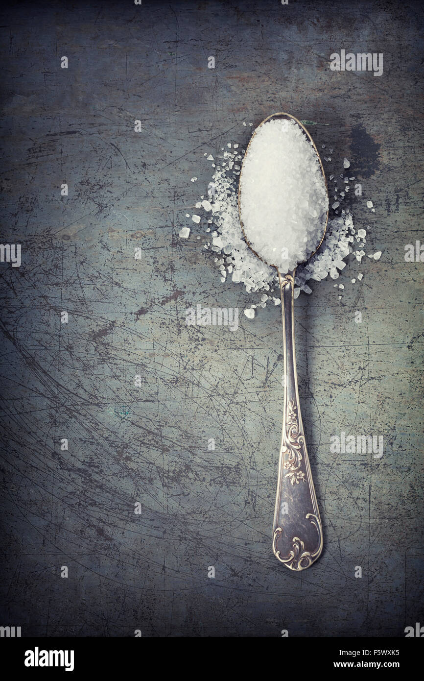 silberner Löffel gefüllt mit Salz auf Rustick Hintergrund Stockfoto