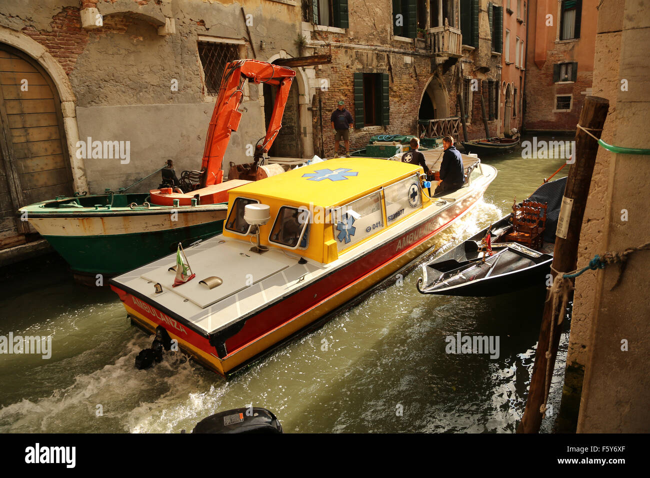 Venedig Ambulanz Boot vorbei an einem Bauherren Boot hat einen kleinen Kran. Stockfoto