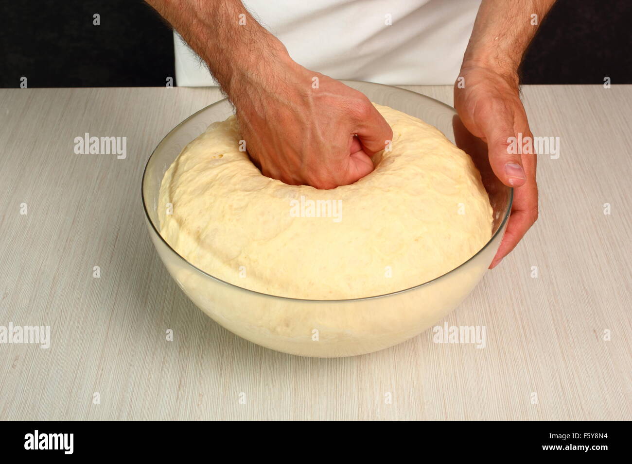 Teig nach steigenden, Schlag nach unten das Zentrum mit der Faust. Herstellung von Hefe-Brötchen-Brötchen Stockfoto