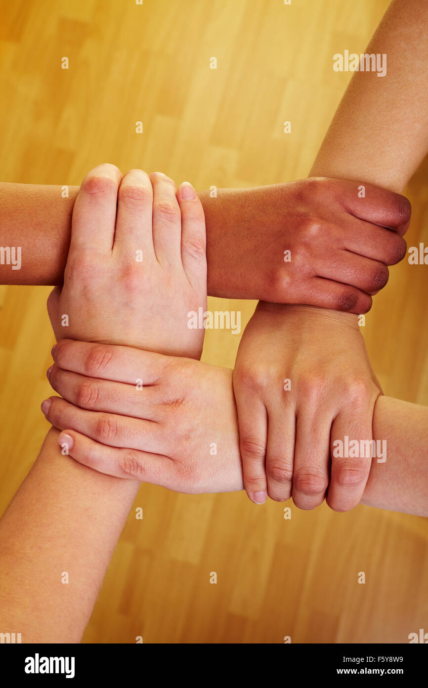 Vier Hände halten einander an den Handgelenken Stockfoto