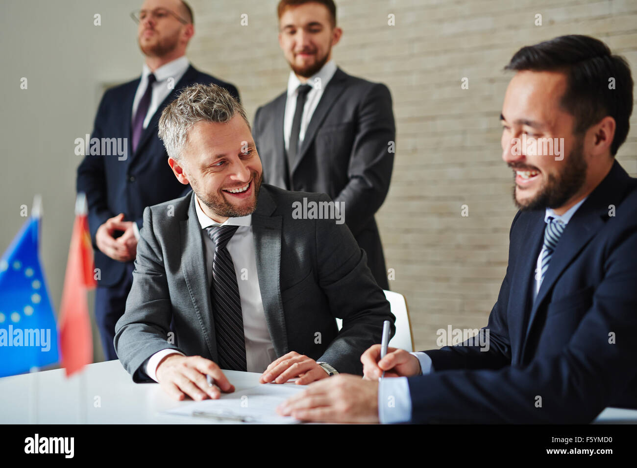 Fröhliche Geschäftsleute am Tisch sitzen und lachen während einer Besprechung Stockfoto