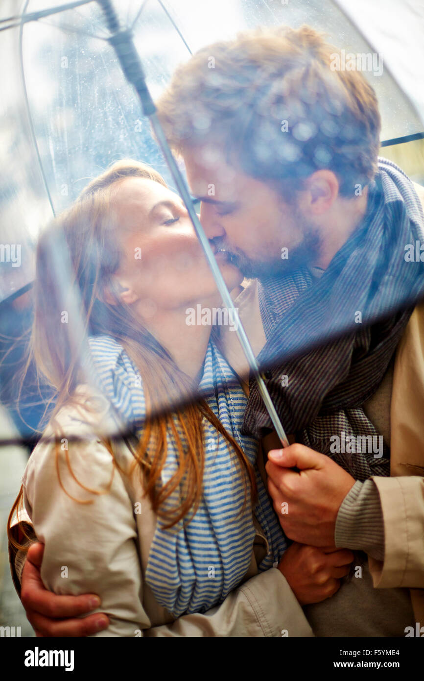Schönes Paar küssen draußen im Regen Stockfoto