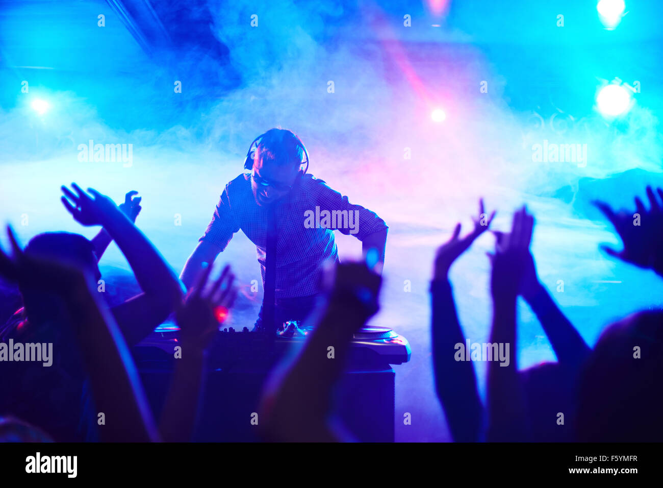 Energetische Deejay stand vor tanzenden Menschen im club Stockfoto