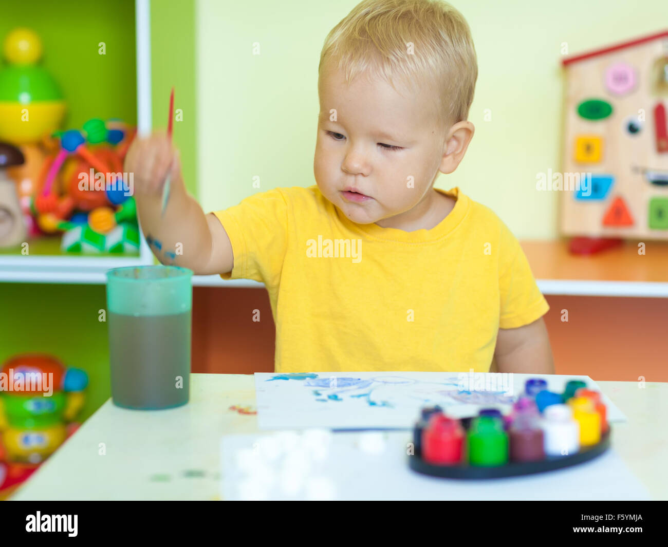 Kleinkind Jungen Praxis auf dem Papier sitzt am Tisch im Kinderzimmer malen Stockfoto