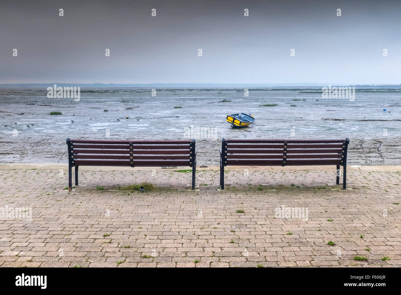 Zwei Bänke auf einer Werft mit Blick auf die Mündung der Themse in Essex. Stockfoto