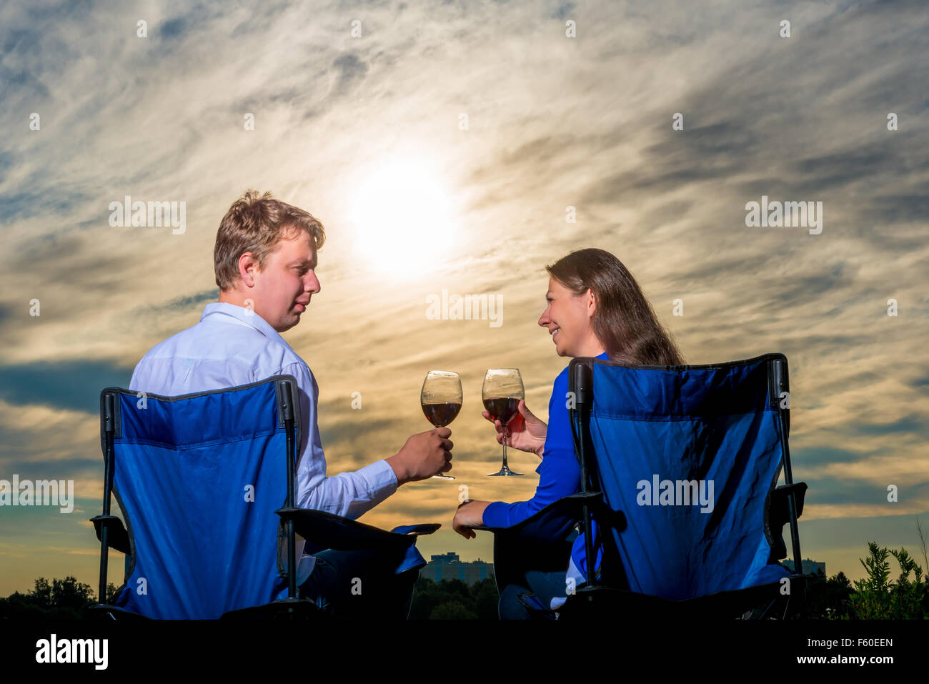 glückliche junge Ehepaar mit einem Glas Wein bei Sonnenuntergang Stockfoto