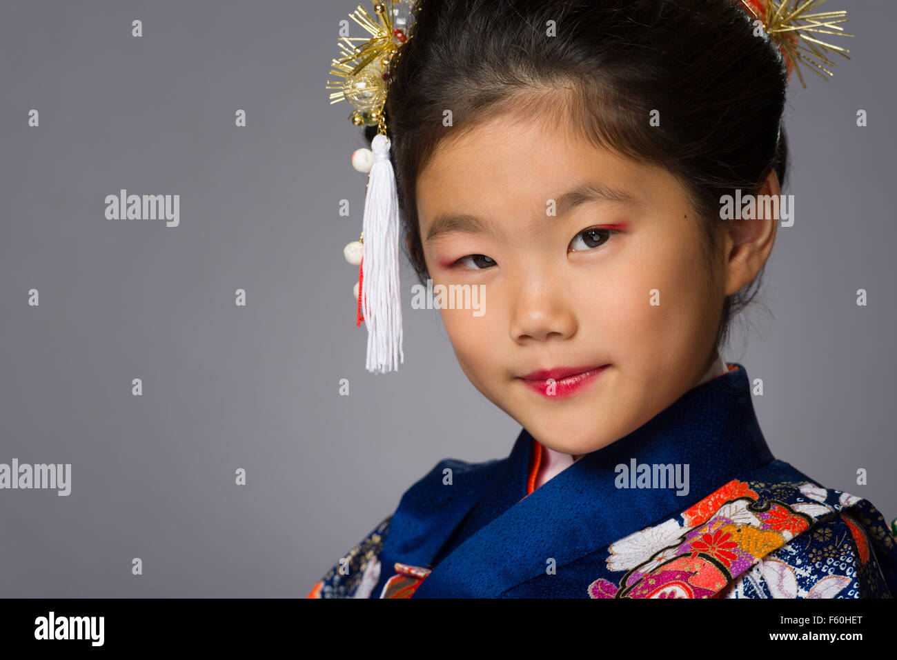 Eine süße junge japanische Mädchen trägt einen Kimono auf grauem Hintergrund. Stockfoto