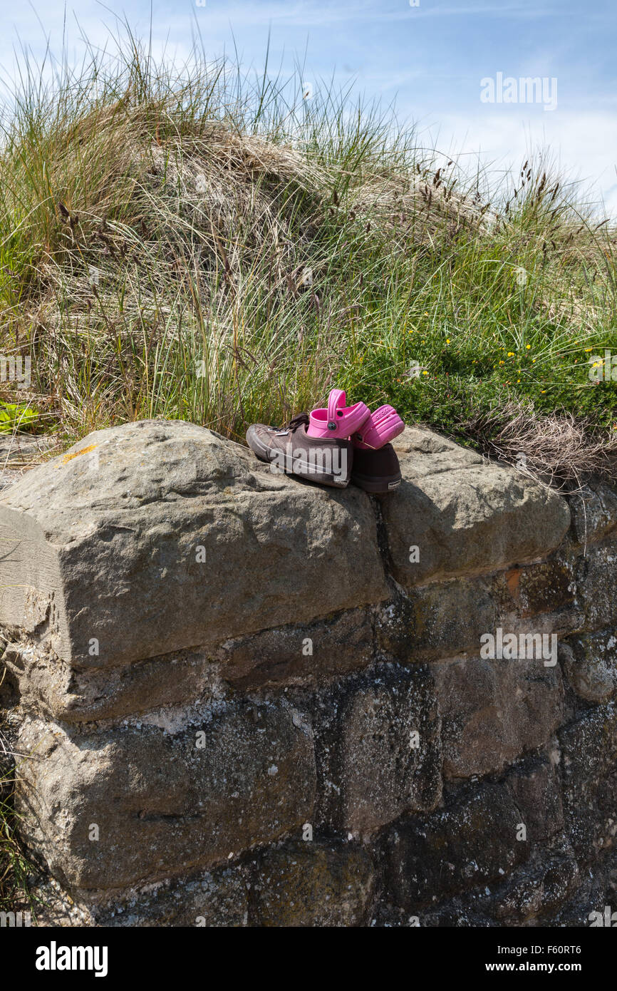 Ein Kinder rosa Schuhe versteckt in ein Paar Turnschuhe von der Hafenmauer zu Seaton Schleuse, Tyne and Wear, England, Uk Stockfoto