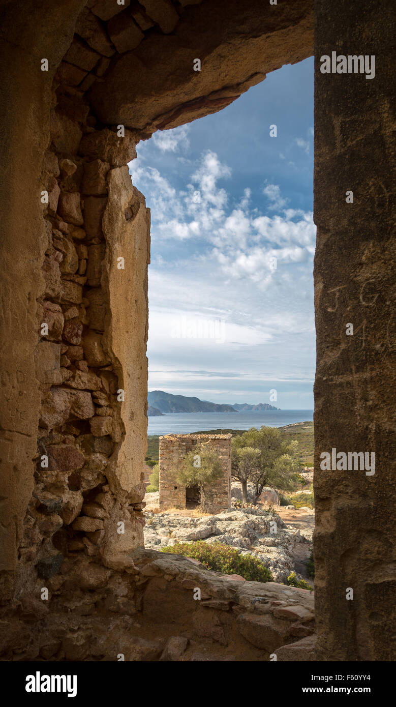 Blick auf verfallene Gebäude und die Küste von Korsika, die durch einen steinernen Fensterrahmen des zerstörten Schlosses von Pierre Napoleon B Stockfoto