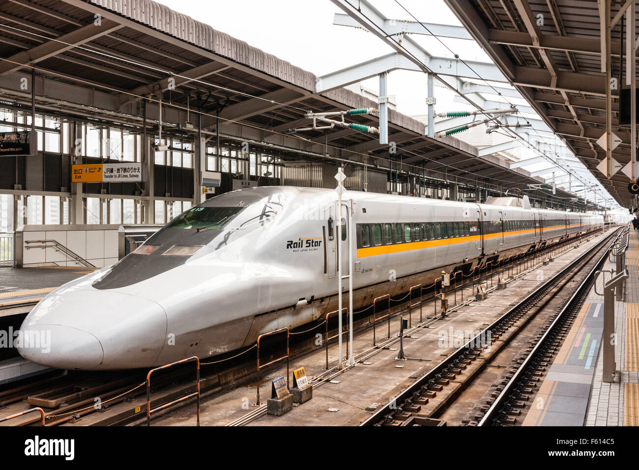 Japan, der Shin-Osaka Station, Osaka. Japanische Hochgeschwindigkeitszug, Shinkansen, 700-Serie, "Star", Hikari, an der Plattform. Weitwinkelaufnahme entlang der Plattform und dem Zug. Stockfoto