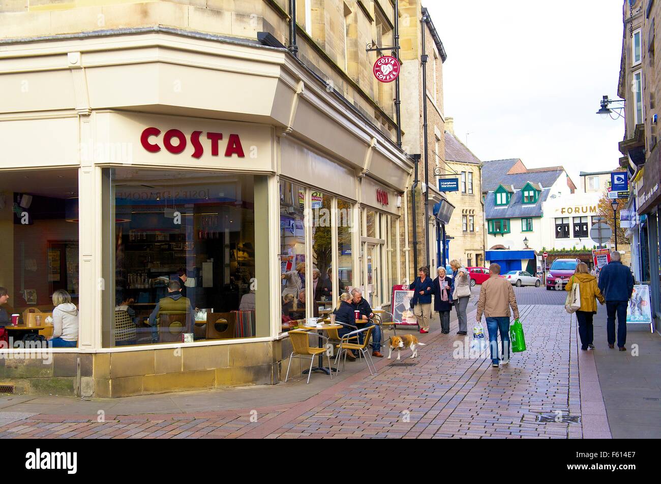 Die Menschen Sie draußen zu sitzen und zu Fuß vorbei an Costa Coffee auf der Ecke Essen Markt / Vorderstraße, Hexham, Northumberland, UK. Stockfoto