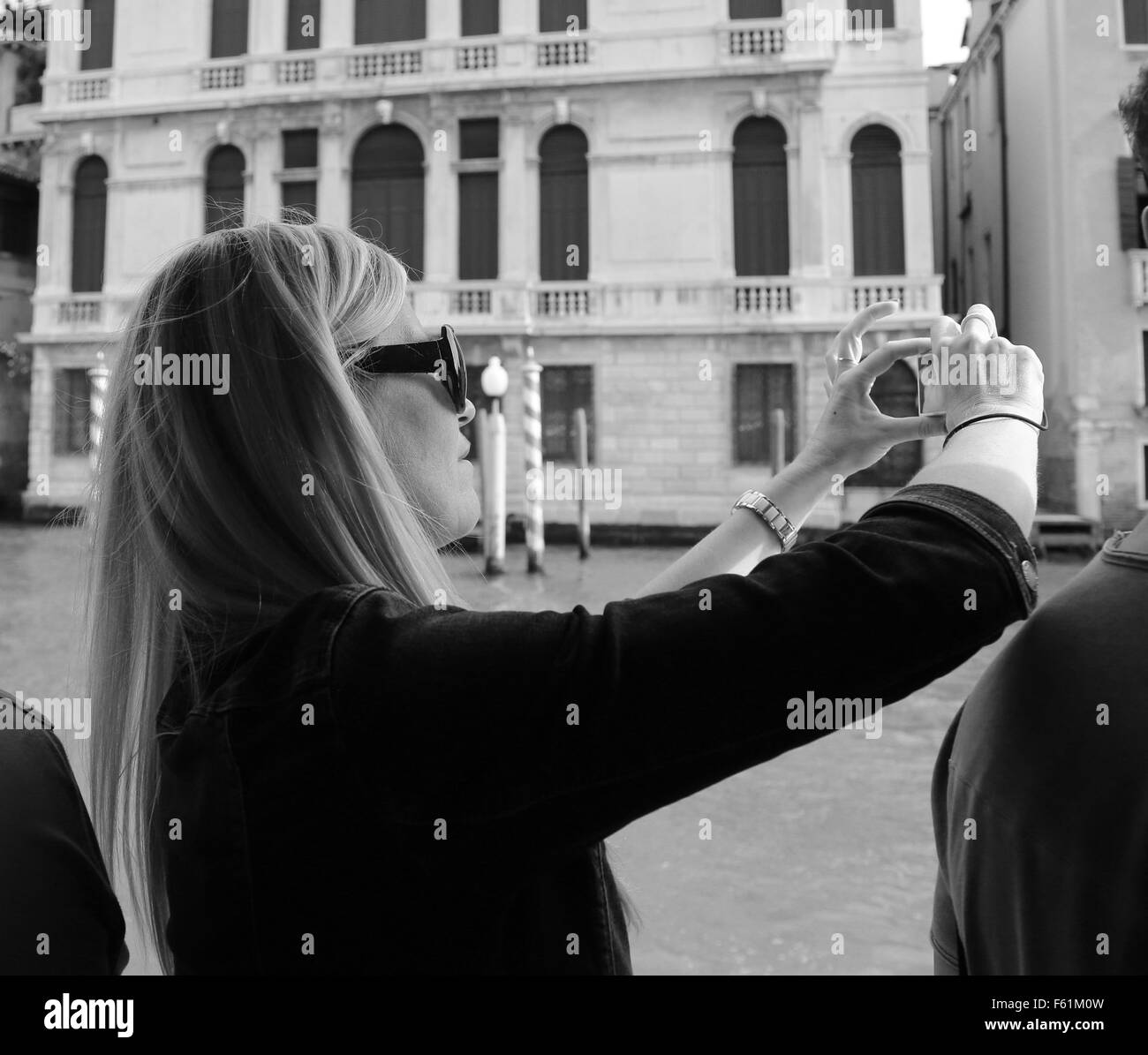 Junge Frau auf einem öffentlichen Verkehrsmitteln Boot in Venedig ein Veperetto's Foto mit ihrem Handy Stockfoto