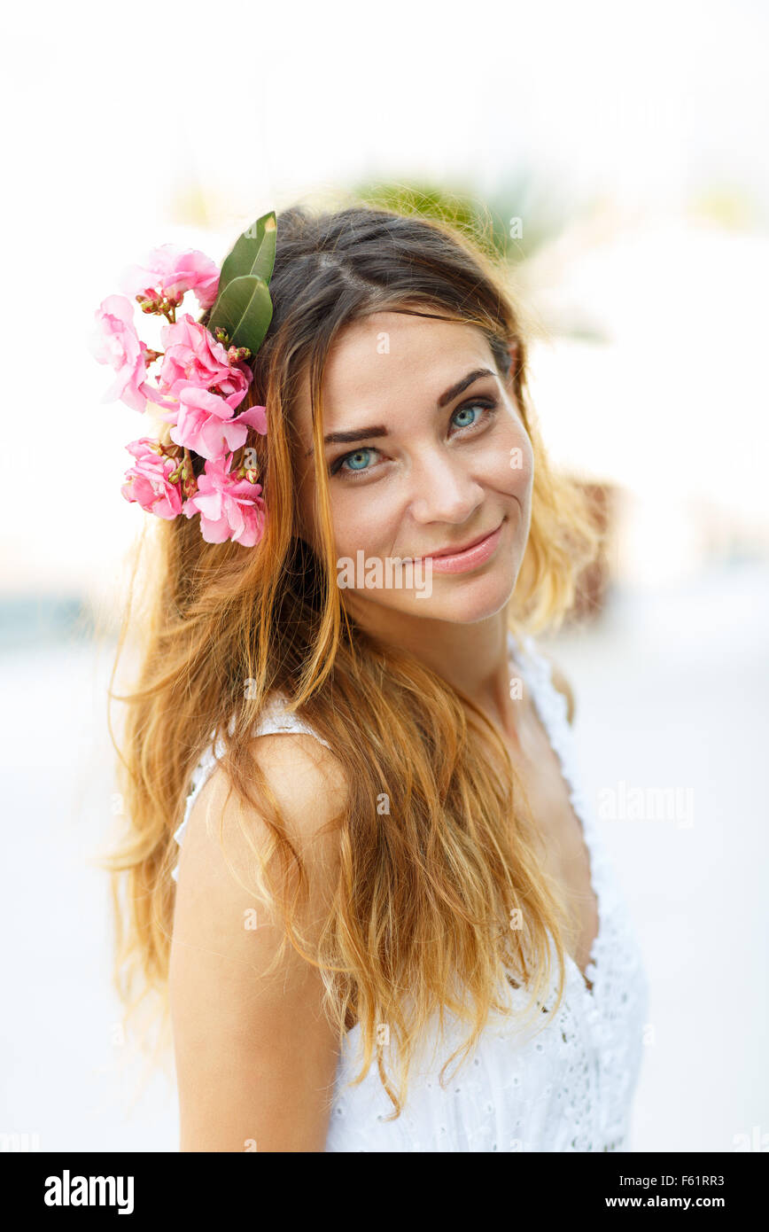 Schöne schöne Frau mit Blume-Haar-Accessoire auf der Straße an einem sonnigen Tag Stockfoto