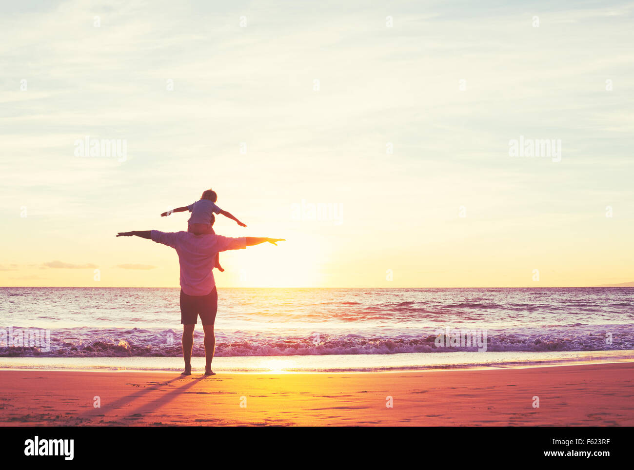 Vater und Sohn spielen am Strand bei Sonnenuntergang Stockfoto