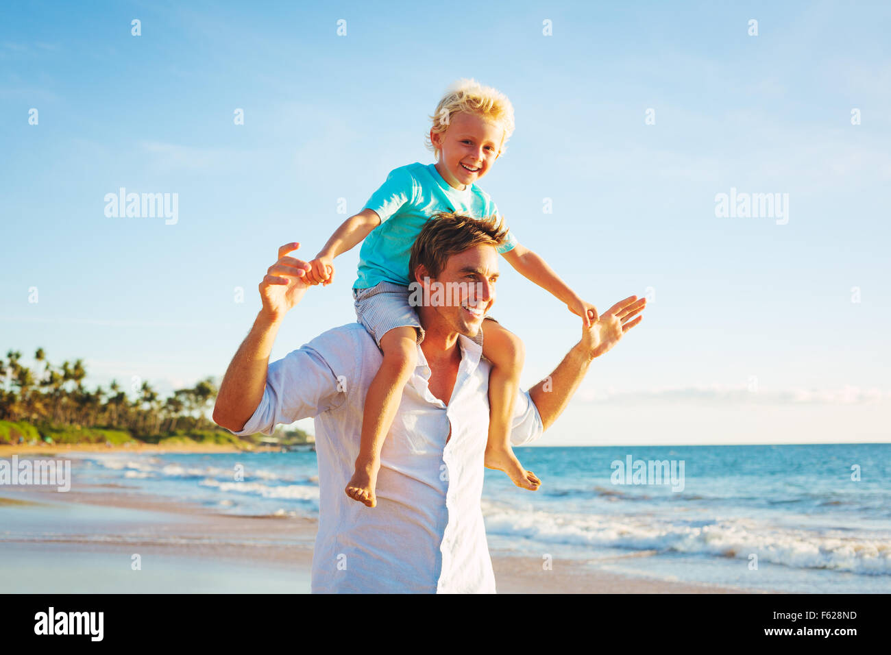 Vater und Sohn spielen und Wandern am Strand bei Sonnenuntergang Stockfoto