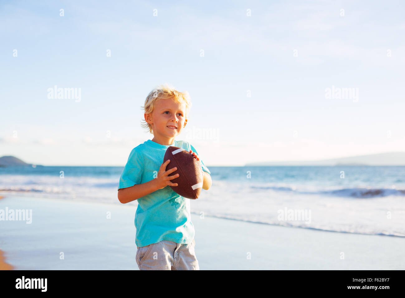 Kleiner Junge werfen Fußball am Strand fangen spielen Stockfoto