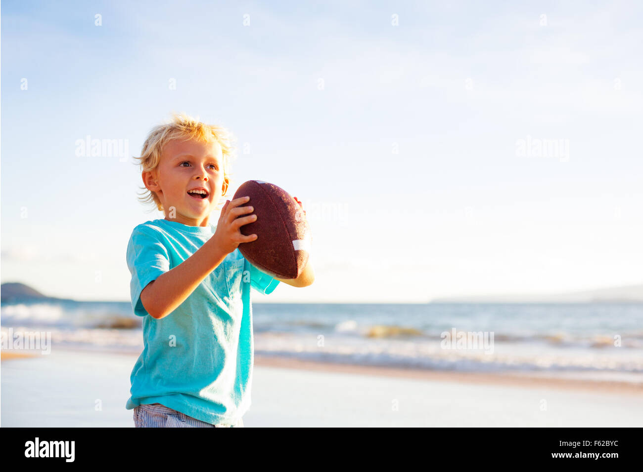 Kleiner Junge werfen Fußball am Strand fangen spielen Stockfoto