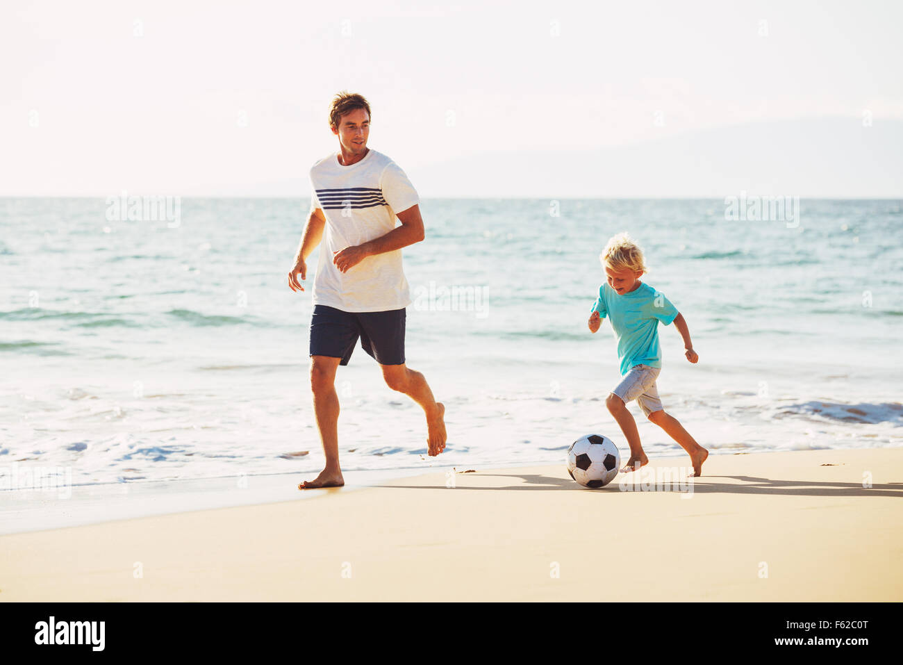 Glücklicher Vater und Sohn Spaß Fußball spielen am Strand Stockfoto