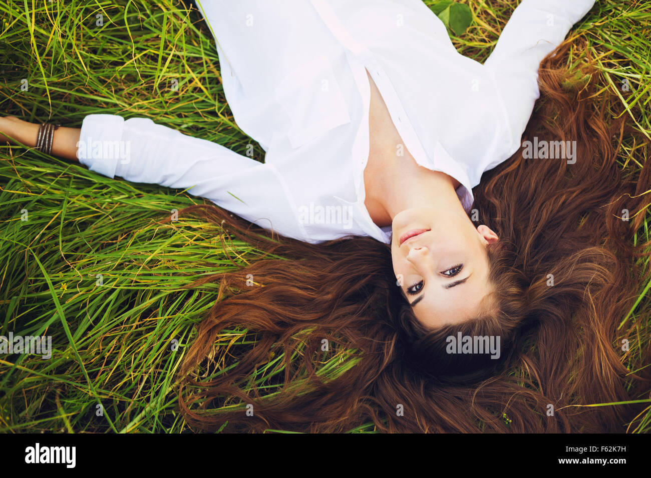 Schöne junge Frau entspannt draußen im grünen Rasen Stockfoto