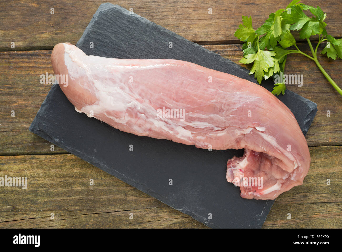Rohe Schweinefilet und Petersilie auf auf einem rustikalen Holztisch Stockfoto