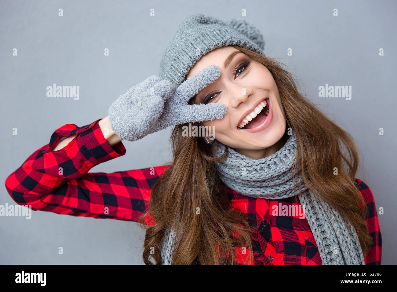 Porträt der Frau zeigt zwei Finger Zeichen auf grauem Hintergrund Lachen lustig Stockfoto