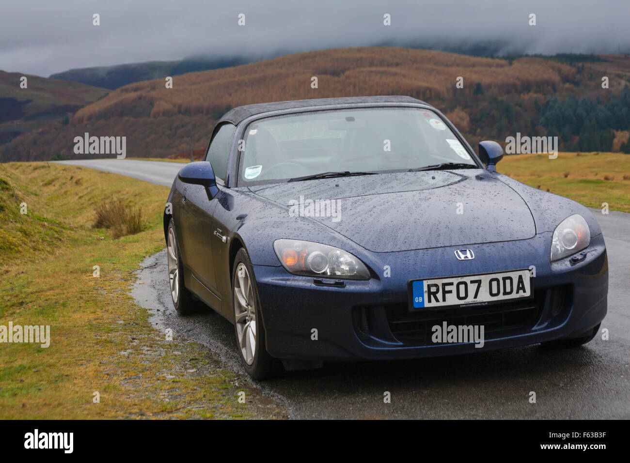 Blauer Honda S2000 Roadster, der an einem regnerischen Tag im November am Llyn Brianne Reservoir, Mid Wales, UK geparkt wurde Stockfoto