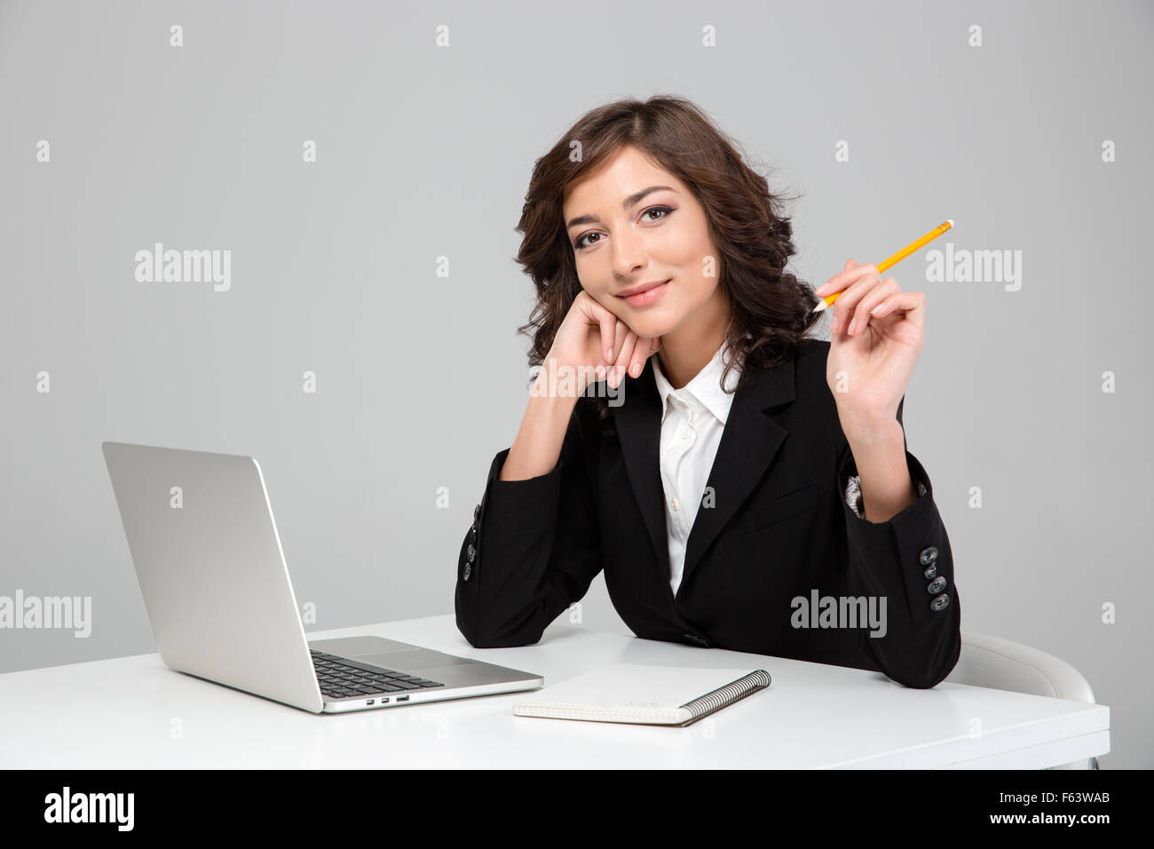 Junge lockig lächelnd gerne hübsche Frau arbeiten mit Laptop und schreiben in Notebook Stockfoto