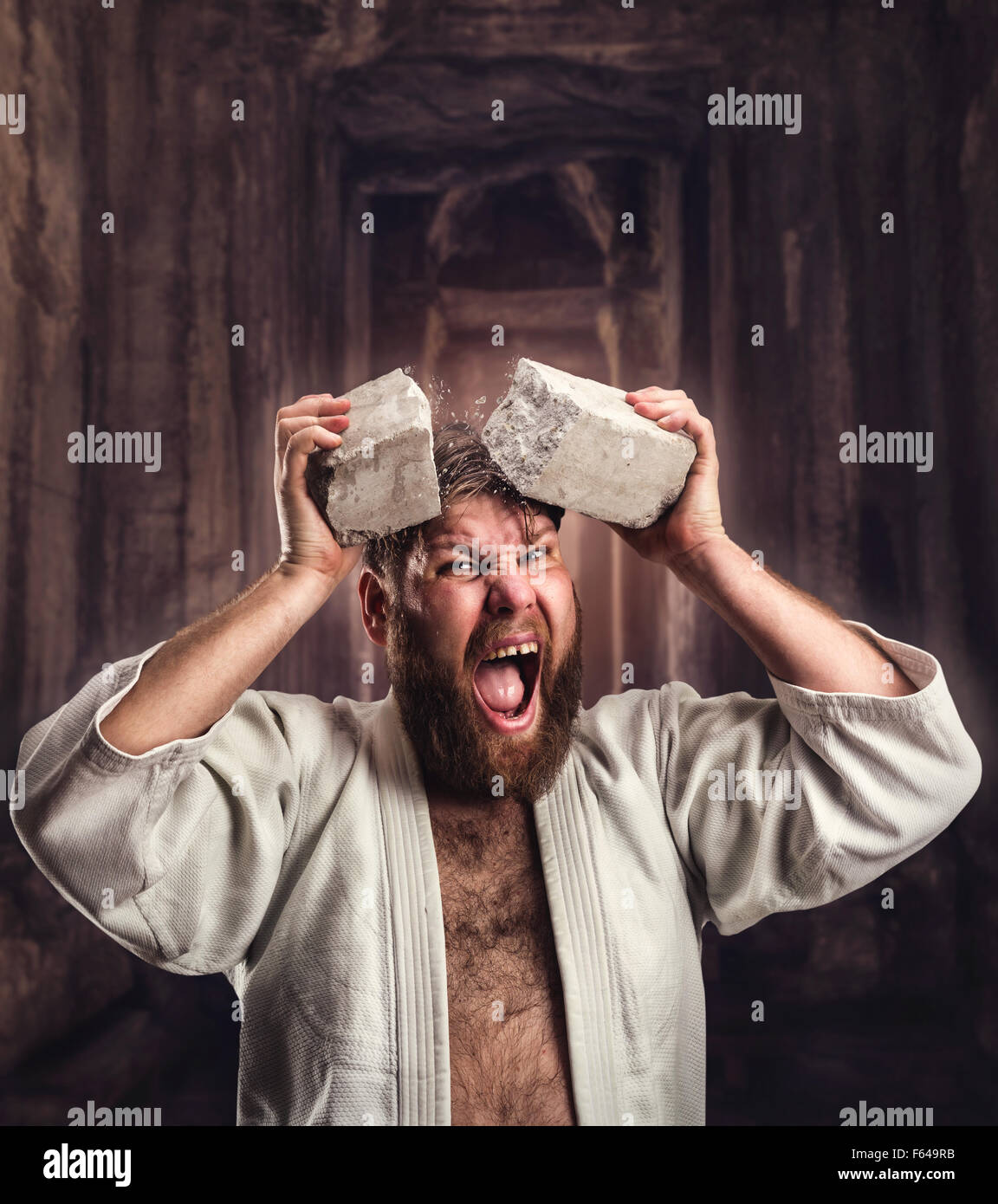 Starke Karateka bricht ein Ziegelstein auf den Kopf im Tempel Stockfoto