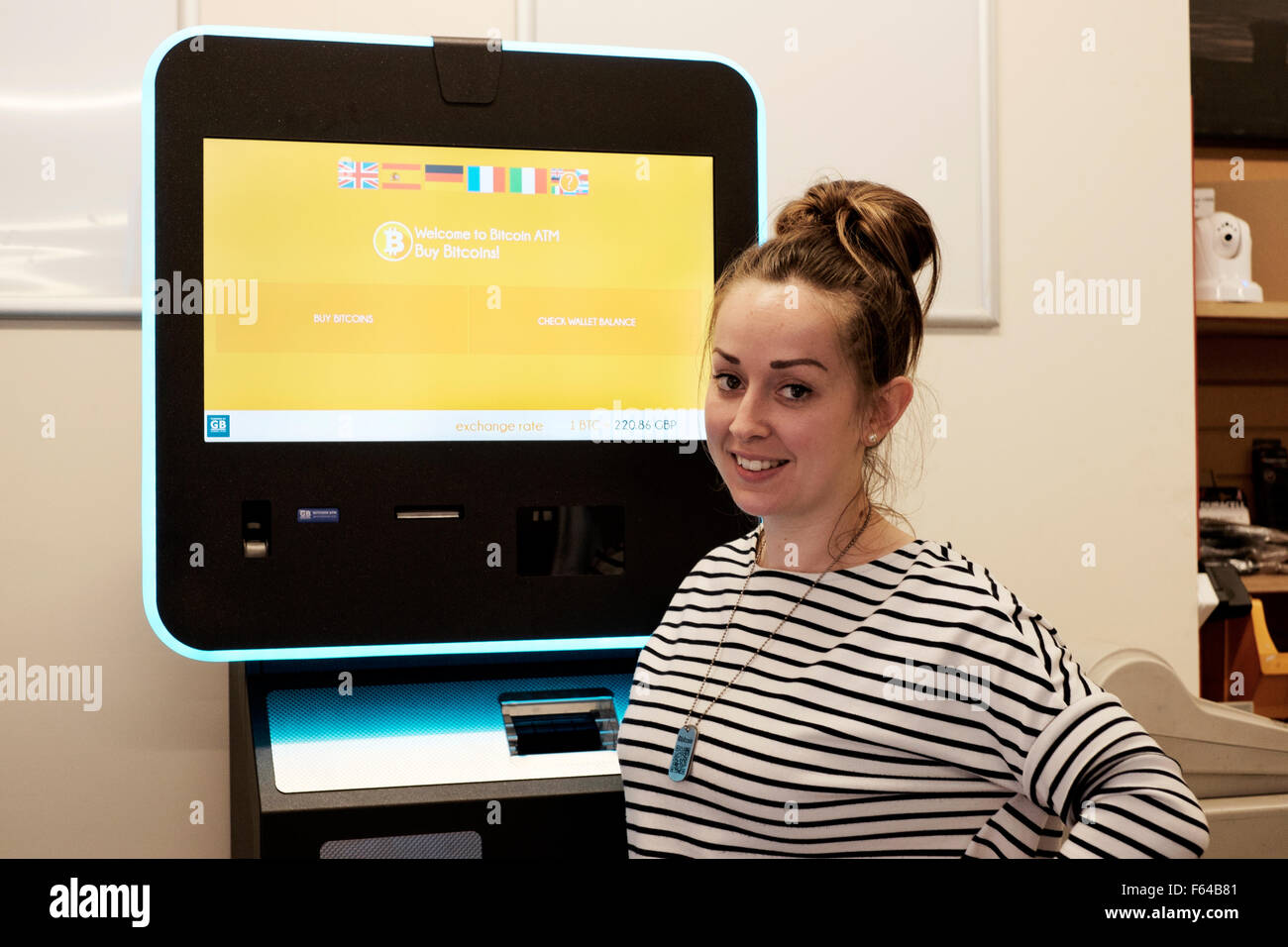 lächelnde junge Frau mit einem digitalen Währung Bitcoin atm England uk Stockfoto