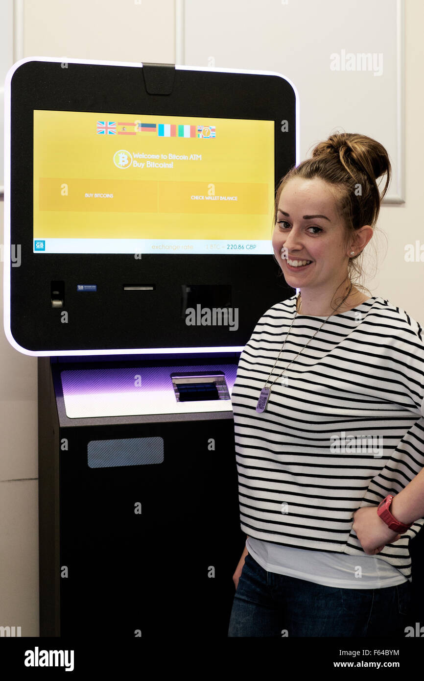 lächelnde junge Frau mit einem digitalen Währung Bitcoin atm England uk Stockfoto