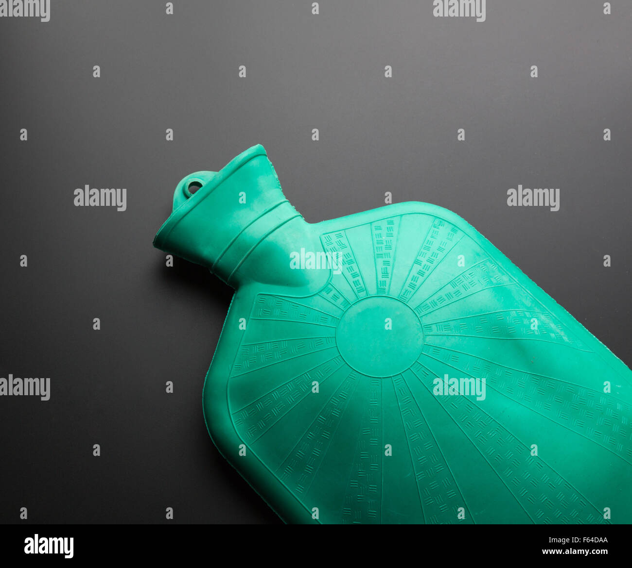 Grüne Gummi-Wärmflasche auf grauem Hintergrund Stockfoto