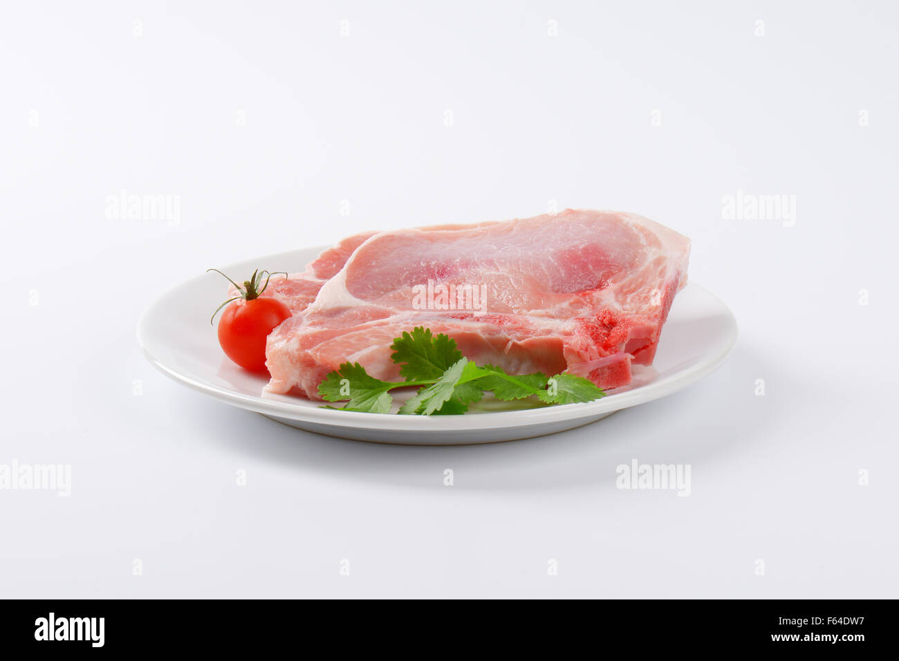 Rohe Schweinekoteletts auf weißen Teller Stockfoto