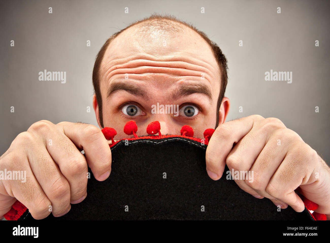 Sehr überrascht Mann versteckt sich hinter Sombrero-Hut Stockfoto