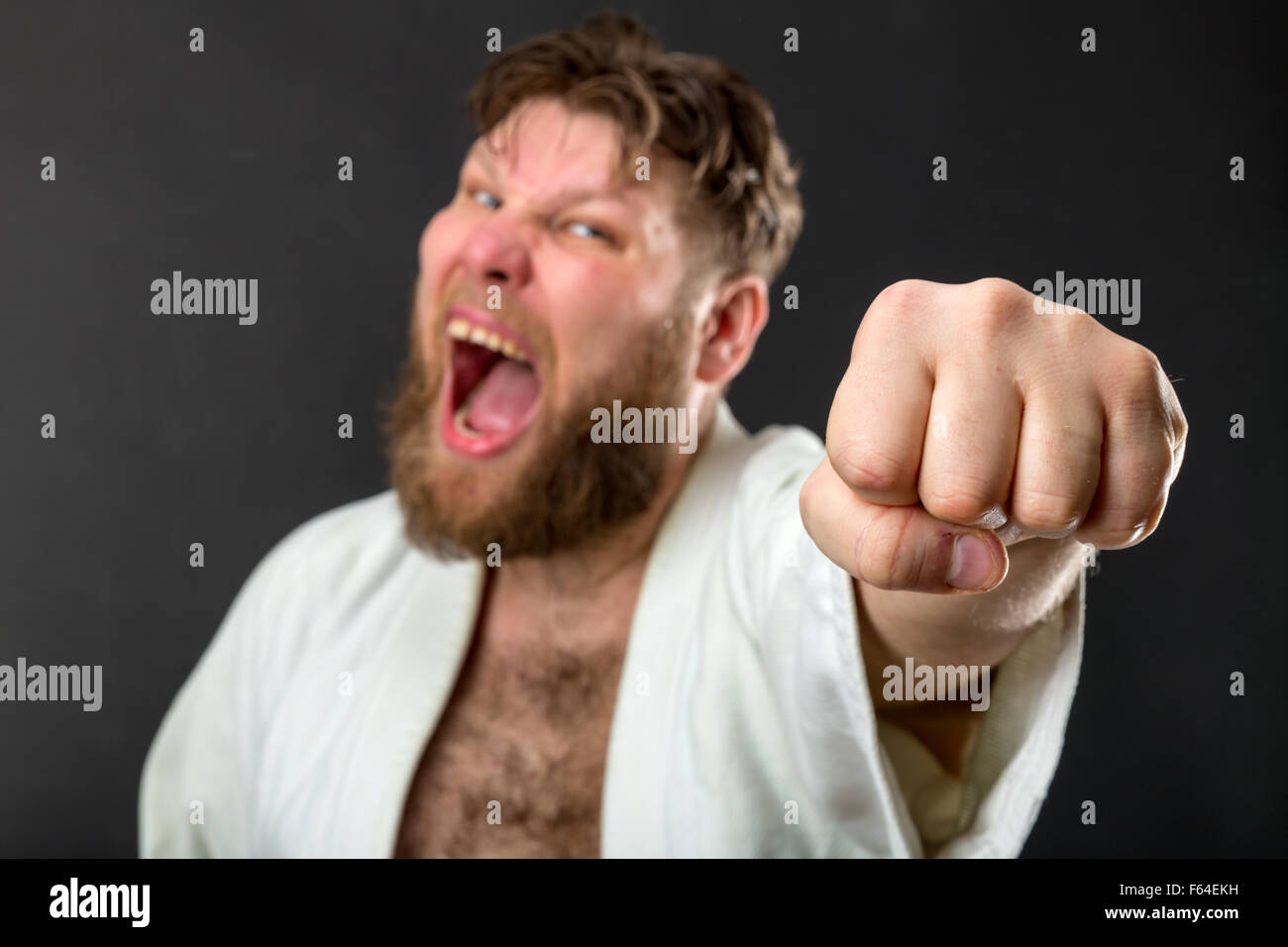 Wahnsinnig starke Karateka in weißen Kimono über grau Stockfoto