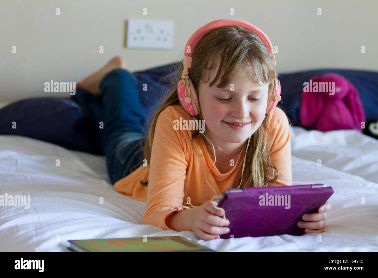 Mädchen arbeiten an iPad Mini mit Kopfhörer Stockfoto