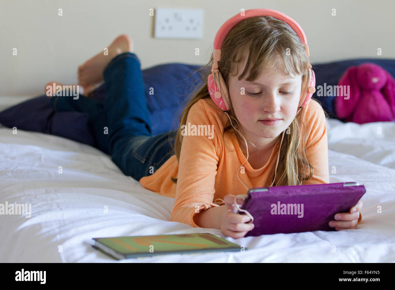 Mädchen arbeiten an iPad Mini mit Kopfhörer Stockfoto