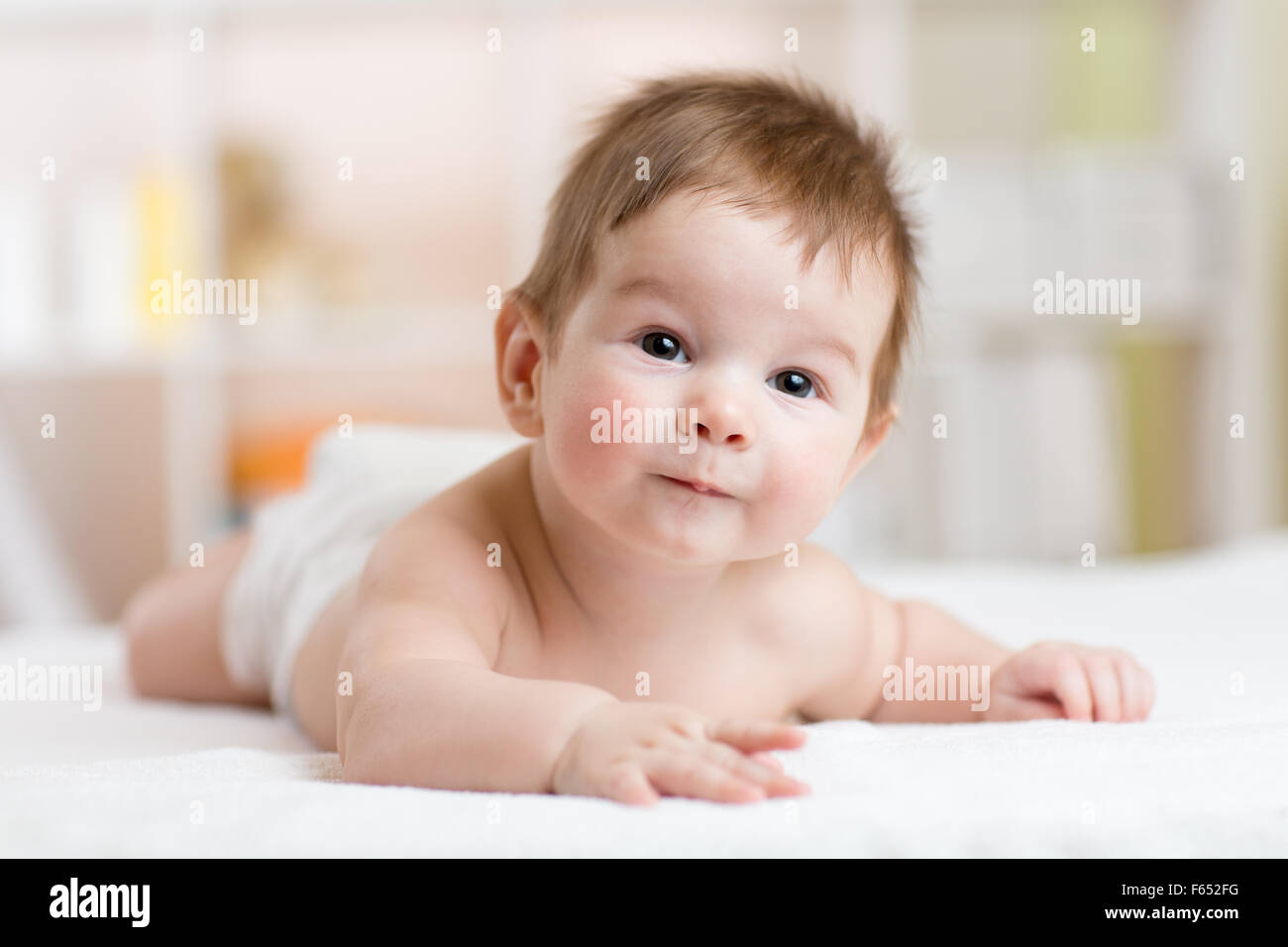 glückliches kleines Baby auf dem Bauch liegend und lächelnd Stockfoto