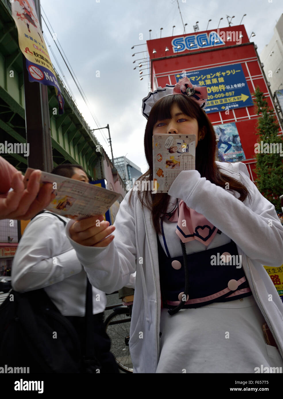 Tokio, Japan. 11. November 2015. Popularität der Maid Cafés in Akihabara Bezirk von Tokio, Japan, führte zu mehr Wettbewerb und ungewöhnlichen Taktiken, um Kunden zu gewinnen. Sehen Sie hier eine junge Frau in ein französisches Dienstmädchen Kostüm Flyer, damit geht die um Passanten zu erbitten. © Rory frohe/ZUMA Draht/Alamy Live-Nachrichten Stockfoto