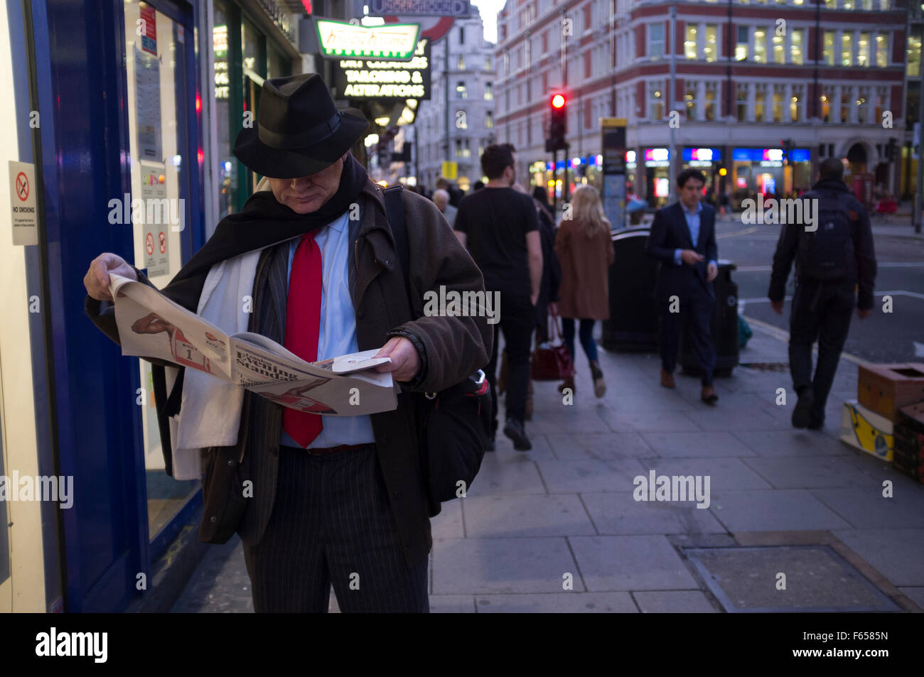 Eine Stadt Gent vertieft in den Evening Standard Zeitung auf eine Londoner Straße am frühen Abend Stockfoto