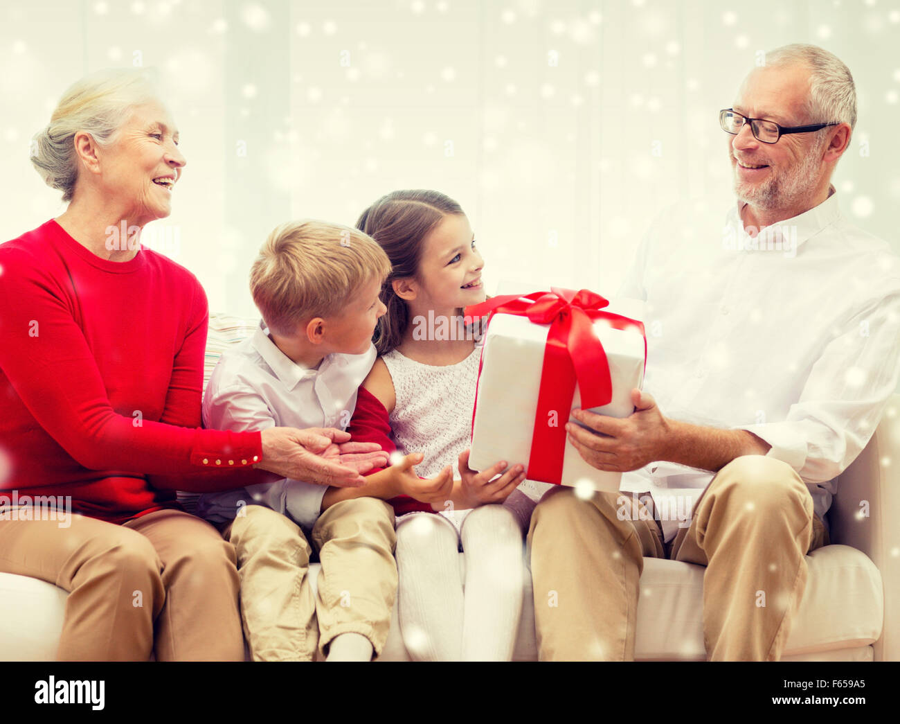 lächelnd, Großeltern und Enkelkinder mit Geschenk Stockfoto