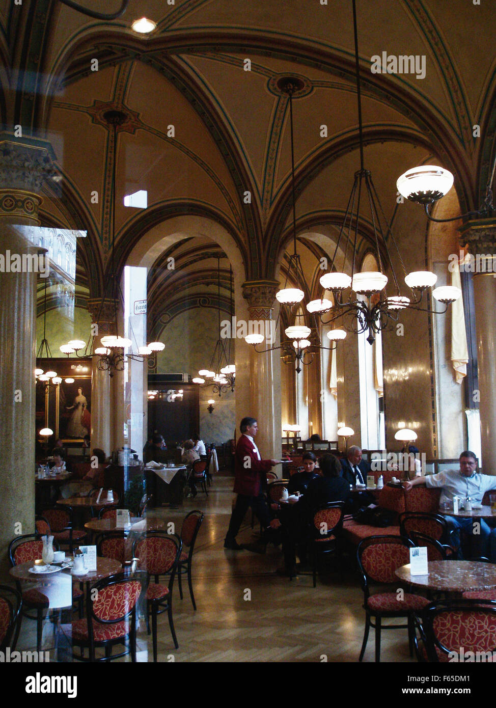 Blick auf rote Stühle und Kellner serviert im Cafe Central im Palais Ferstel, Wien, Österreich Stockfoto