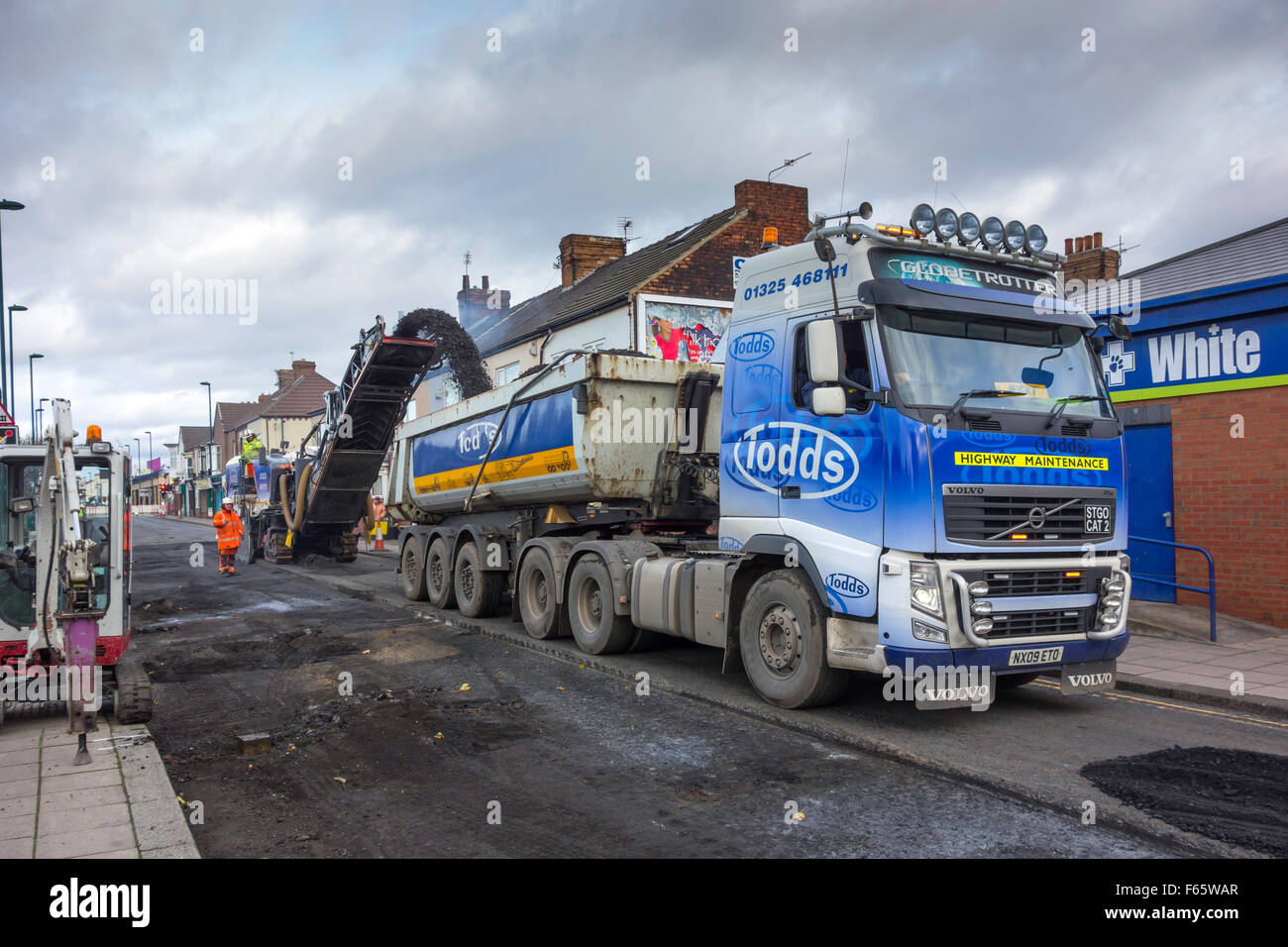 Eine Straße, die Maschine in Aktion auf einer Straße Oberflächenersatz Auftrag Ableitung des Ausbruchmaterials Oberfläche in einen LKW Planen Stockfoto