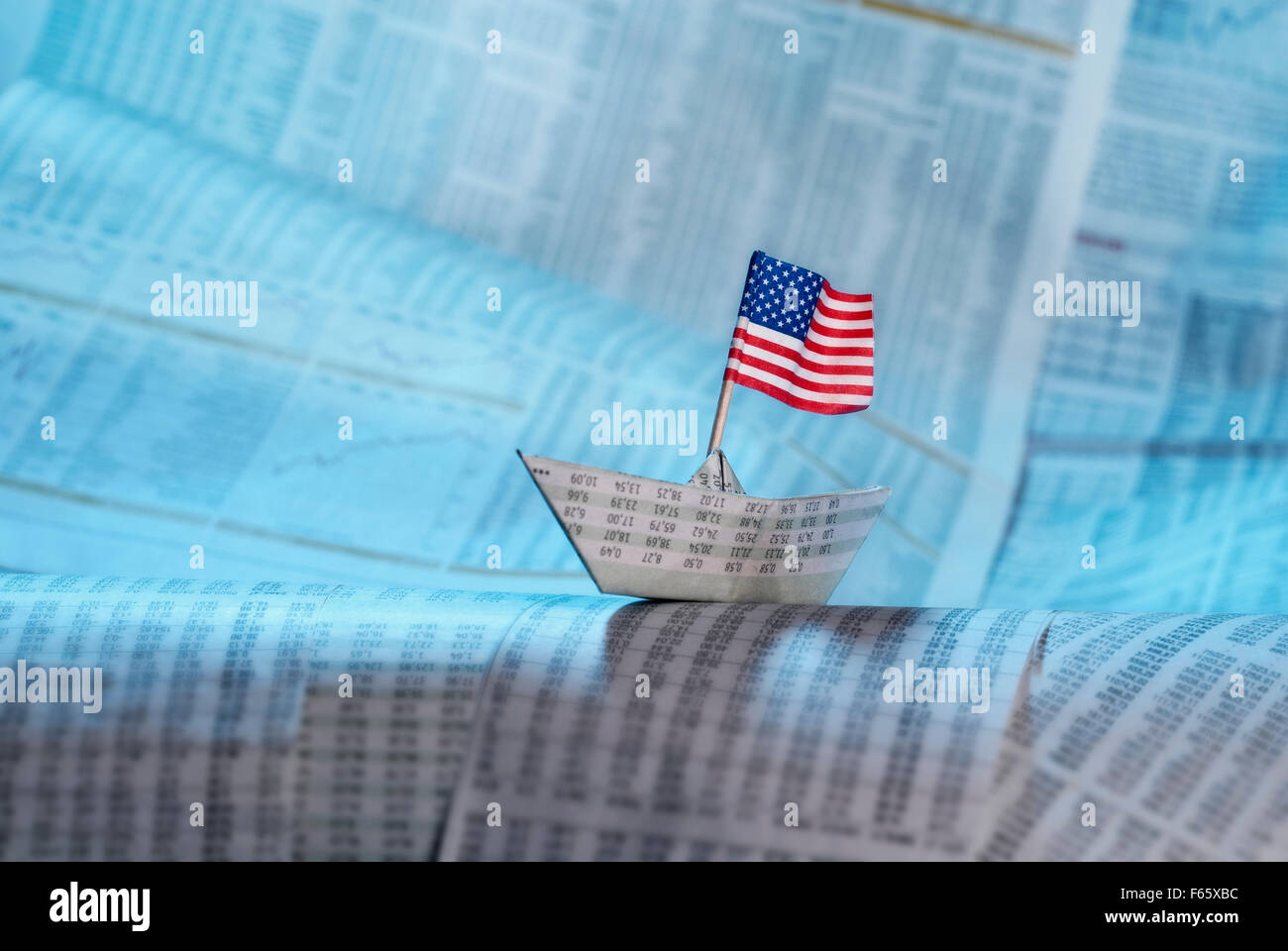 Papier Schiff mit amerikanischer Flagge auf Zeitungsseiten mit Tarifpreistabellen. Stockfoto