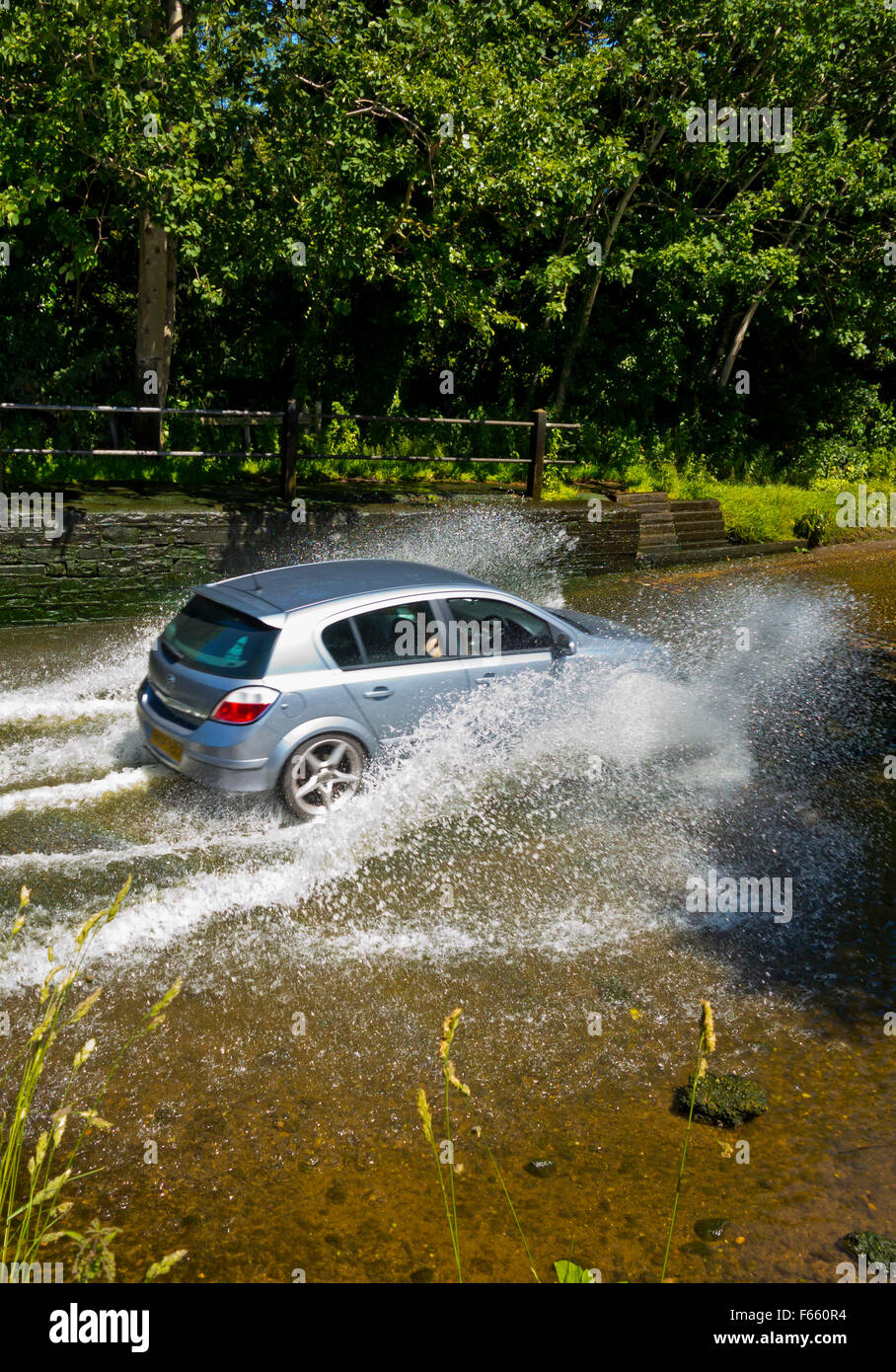 Auto fahren durch ein Wasser gefüllt Ford über einen Bach auf einer Landstraße in England UK Stockfoto